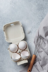 White eggs in a small paper container box top view on a neutral background