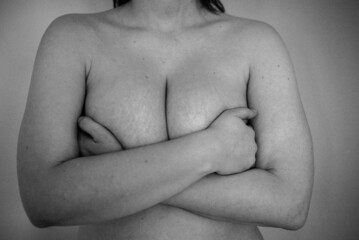 black and white photo of a naked woman holding her breasts
