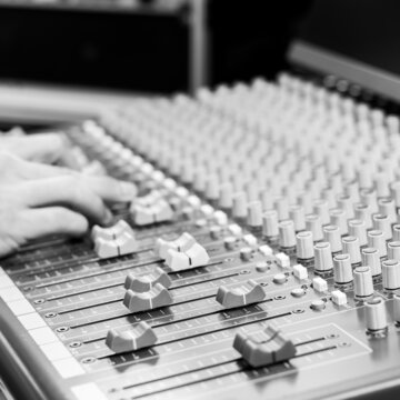 out of focus sound engineer hands working on audio mixing console. focus on fader