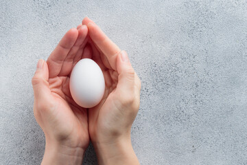 Human hands holding a white egg