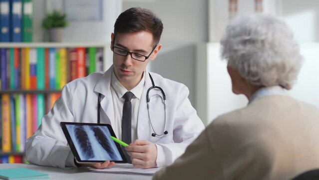 Radiologist discuss x-ray with aged patient in medical center