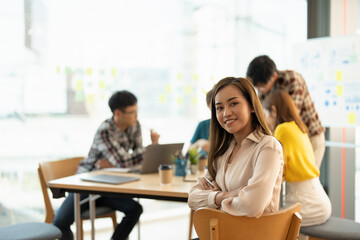 Fototapeta premium Attractive young Asian business woman smiling and looking over shoulders at business meeting with co-workers