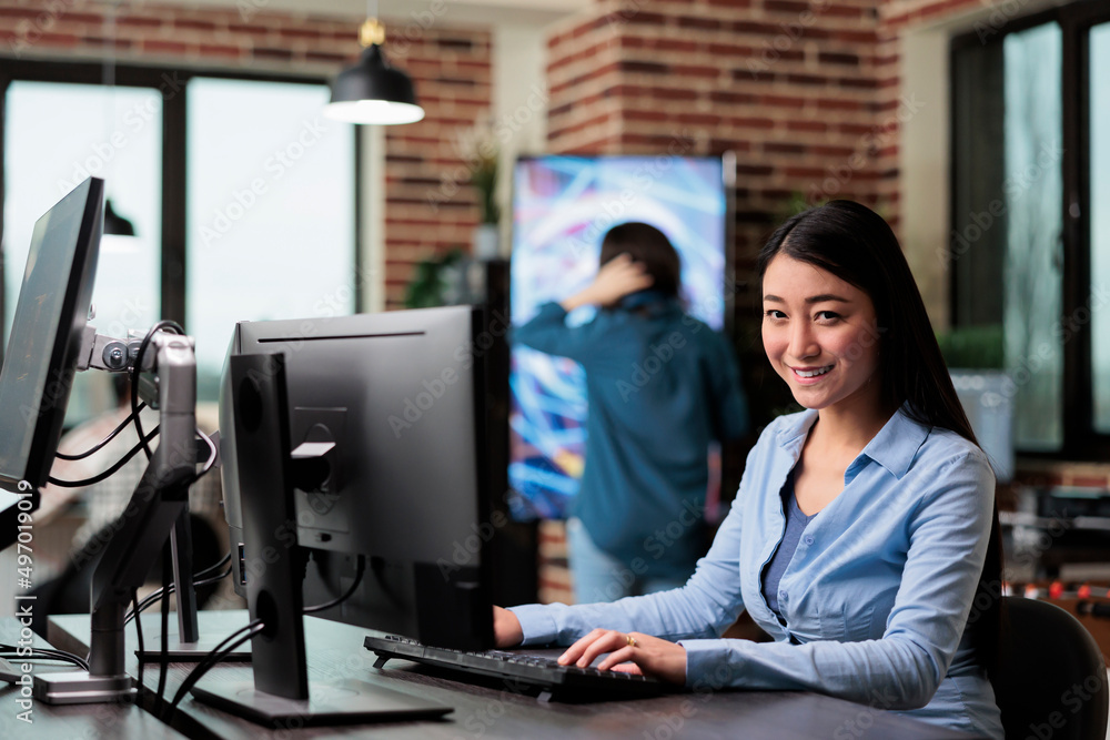 Poster smiling 3d artist and developer sitting at desk in office workspace while working on new game projec