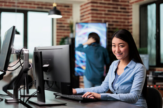 Smiling 3D artist and developer sitting at desk in office workspace while working on new game project. Creative agency digital artist using professional skill to improve videogame quality. - Powered by Adobe
