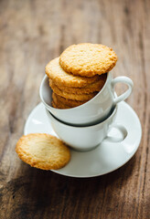 Freshly baked coconut cookies arranged in a tea cup and saucer. An elegant food photography.