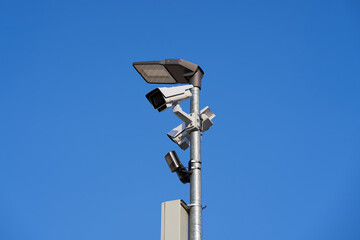 Security cameras on a pole against a blue sky. 