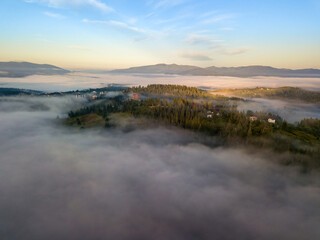 The rays of dawn over the fog in the Ukrainian Carpathians. Aerial drone view.