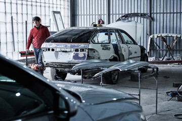 Car service worker repairs restores car