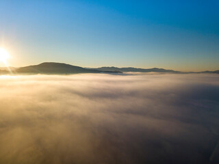 Fototapeta na wymiar Sunny morning in the foggy Carpathians. A thick layer of fog covers the mountains. Aerial drone view.