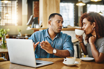 I need your input on this. Cropped shot of a young couple working on a laptop while sitting in a coffee shop.