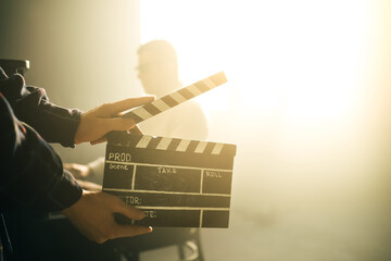 Clapperboard or clipboard in hands. Guy is directing and filming retro cinema or vintage movie. Composer man play on the old piano. - obrazy, fototapety, plakaty
