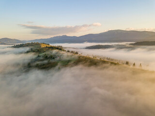 Mountain settlement in the Ukrainian Carpathians in the morning mist. Aerial drone view.