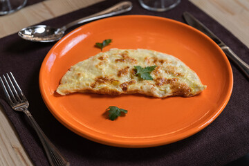 A photo of an omelette is laid out on an orange plate.