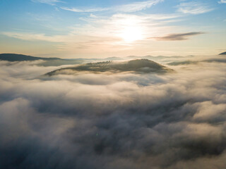 The rays of dawn over the fog in the Ukrainian Carpathians. Aerial drone view.