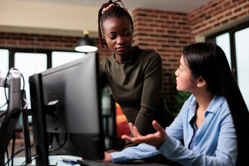 Doubtful woman discussing with production department team leader about digital design flaws. Creative designers conversating about project development roadmap while in office workspace.