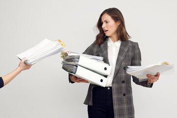 Stressed female worker and business woman holding a pile of paperwork while getting more work to do. Looking frustrated with too much work, isolated on white background. Concept: Too much work	