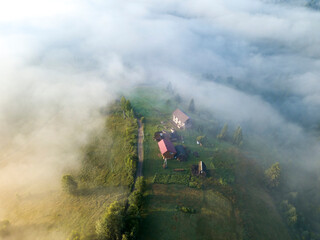 Mountain settlement in the Ukrainian Carpathians in the morning mist. Aerial drone view.