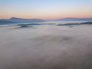 Naklejka na ściany i meble Sunrise over the fog in the Ukrainian Carpathians. Aerial drone view.