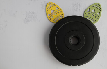 Dumbbells barbell weight plate disc and decorative Easter eggs in shape of bunny ears. Healthy...