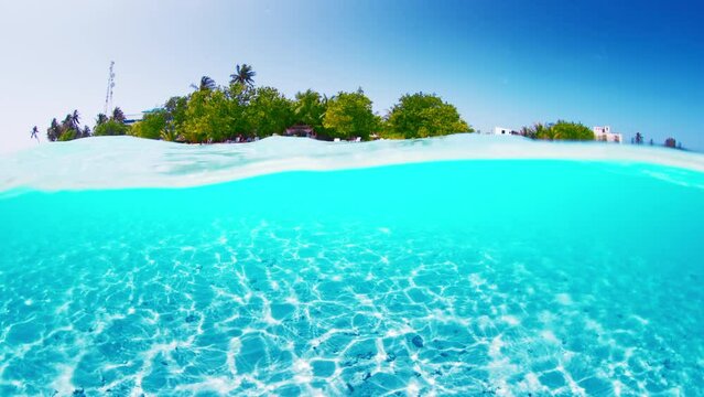 Tropical island of Thulusdhoo in Maldives. Splitted above and underwater view of the idyllic beach resort
