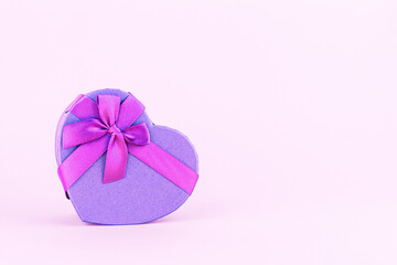 Heart shaped gift box with ribbon and bow on a pink background, front view, copy space. Boxing day.