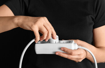 electricity, energy and power consumption concept - close up of woman inserting plug into socket...
