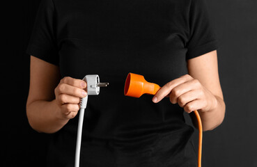 electricity, energy and power consumption concept - close up of woman inserting plug into socket...