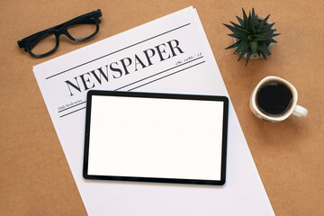 newspaper and white mock up screen tablet with coffee cup on wooden table