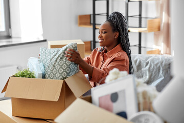 moving, people and real estate concept - happy smiling woman unpacking boxes sitting on sofa at new...