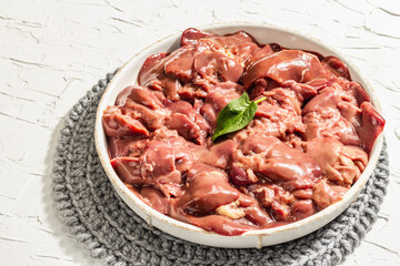 Raw chicken liver in a bowl. Fresh food ingredient and spices, trendy hard light, dark shadow