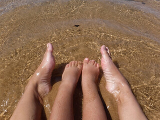 Feet of mom and son on the beach