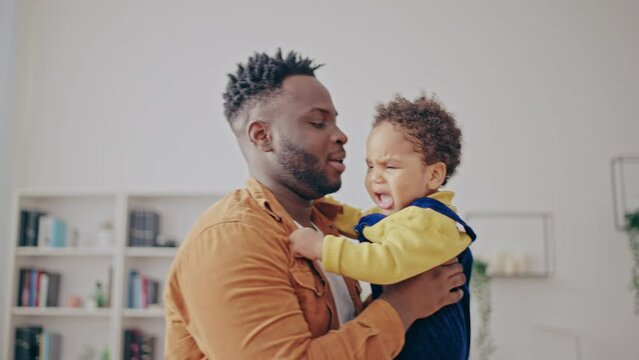Caring father comforting crying baby boy, child suffering from colic or teething