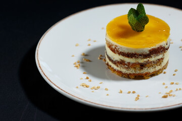 bright yellow diet carrot cake on a dark table, dried orange, cinnamon, nuts, mint leaves, diet confectionery concept