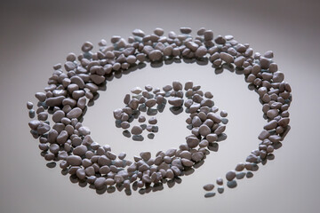 Sassolini grigi disposti a spirale su superficie di vetro