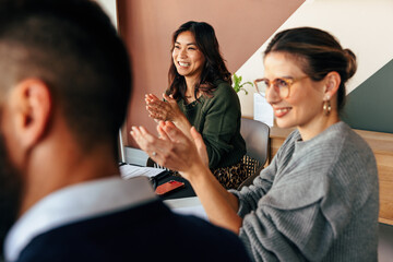 Cheerful businesspeople applauding during a meeting - obrazy, fototapety, plakaty