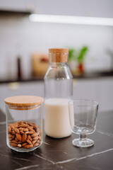 Obraz na płótnie Canvas Almond milk and glass on kitchen counter. Healthy vegan product concept.
