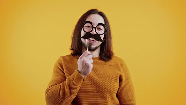 Funny Disguise Concept. Adult Caucasian Man Wearing Fake Glasses And Mustache Over Yellow Background. High Quality 4k Footage