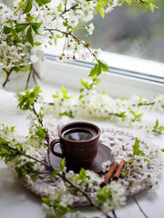 Spring morning, a cup of coffee on the windowsill, blooming white cherry