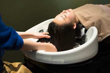 Obraz premium 美容室でシャンプーされる女性