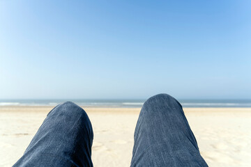 Mit Jeans im Urlaub am Strand liegen