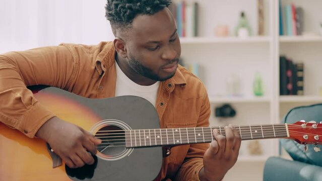 African American man learning to play guitar, musician rehearsing new single