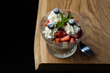 Classic dessert with berries and whipped cream in a glass