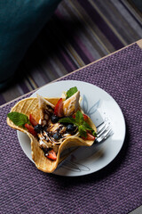 Crispy waffle cone filled with berries, chocolate, ice cream and sponge cake pieces, bright unusual summer dessert, copy space