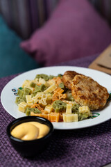 Colorful and funny pasta with two small chicken cutlets, high angle view for a menu