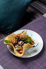 Crispy waffle cone filled with berries, chocolate, ice cream and sponge cake pieces, bright unusual summer dessert, copy space