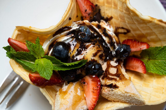 Sundae ice cream with strawberry and blueberry in a waffle cone, close up, appetizing photo