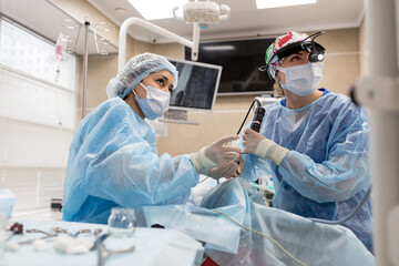 Surgeons operating on a man looking into a screen of health vital signs