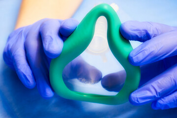 Anesthesia mask. Hands of a medic in gloves and an anesthesia mask front view. Soft filter on the...