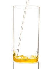 yellow drink - juice, cider, tea or kombucha - pouring into transparent glass isolated over white background. healthy morning vitamin drink