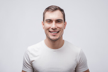 portrait of smiling caucasian man in white T-shirt on white grey background,
